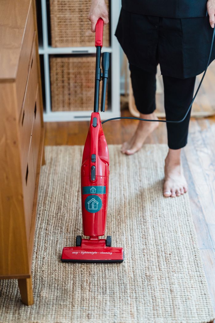 A person vacuuming a carpet barefoot in a modern indoor setting, focusing on clean home aesthetics.